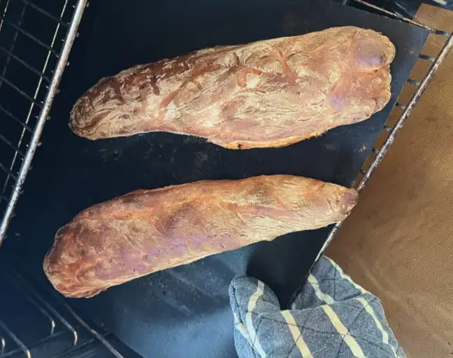A photograph of two homemade baguettes fresh out of the oven.